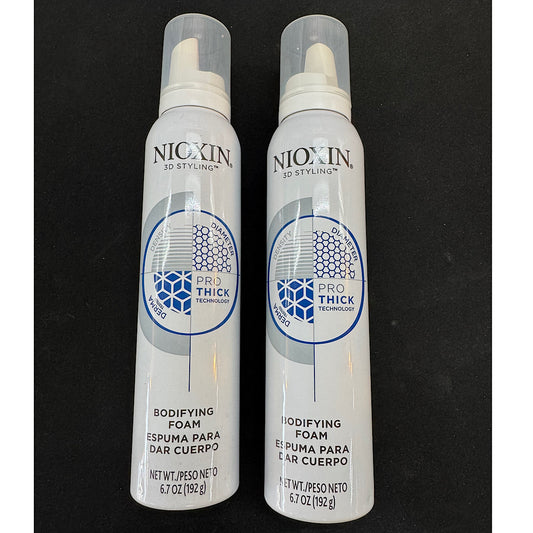Two white Nixxin 3D Styling Pro Thick Technology Bodifying Foam spray cans standing side-by-side on a black background.