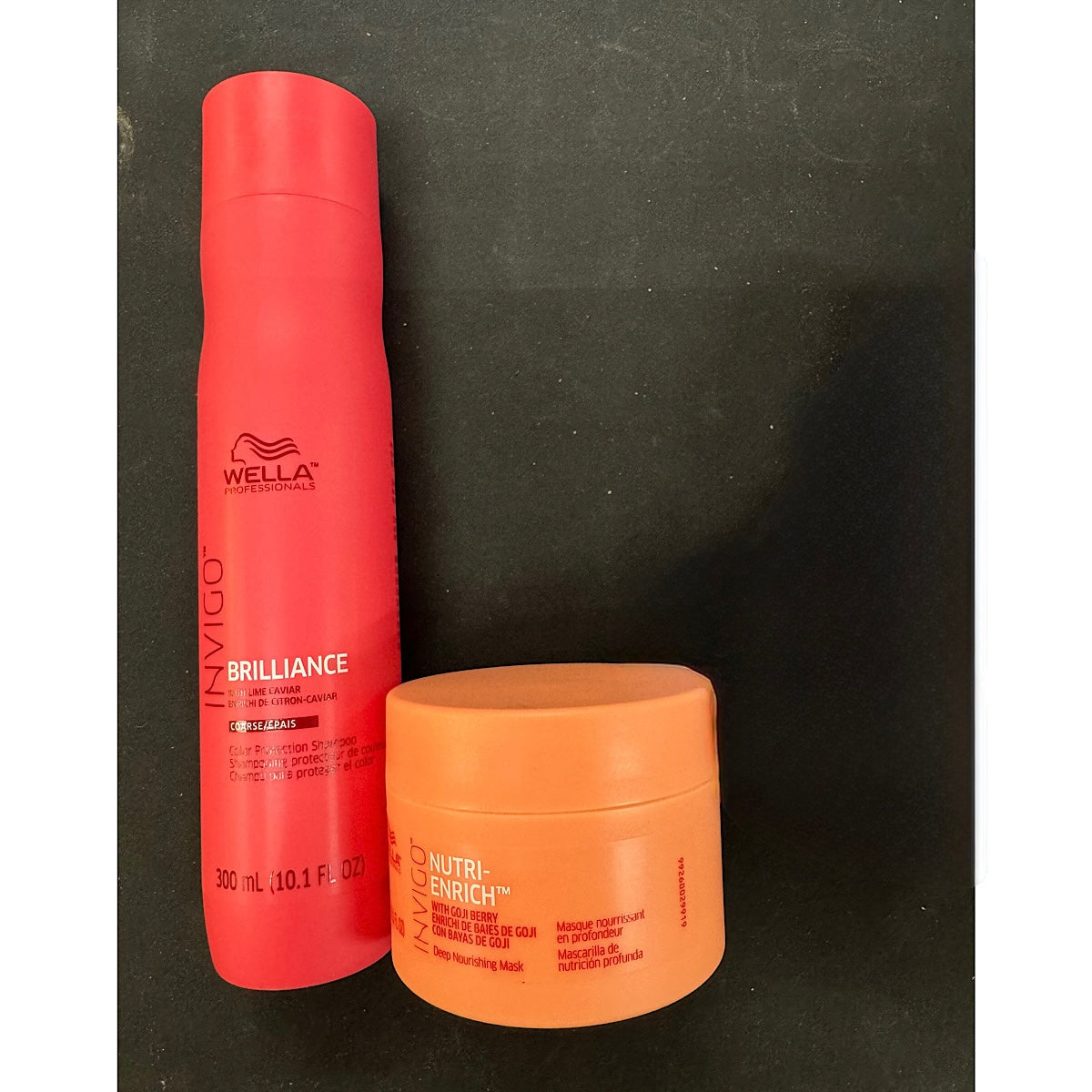 Wella Professionals Invigo Brilliance hair product set featuring a red spray can and an orange jar on a dark background.