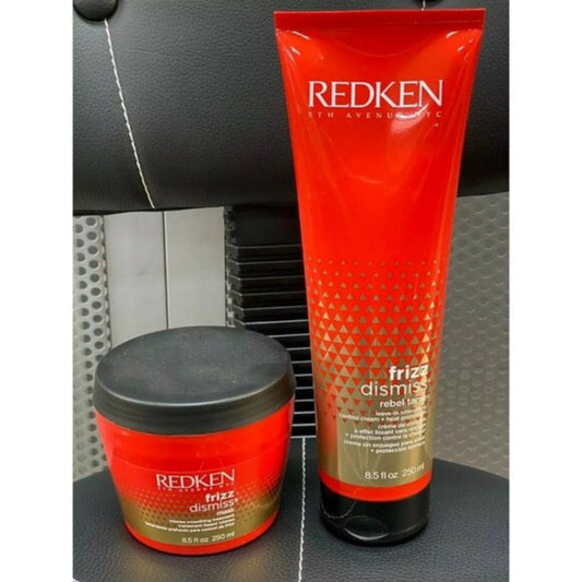 REDKEN Frizz Dismiss Rebel Hair Care set, featuring a 200ml red squeeze tube and a 200g red jar with a black lid, displayed on a black textured leather surface.